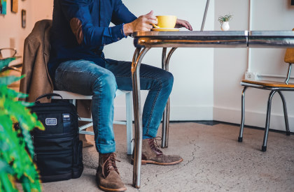 Man zittend aan tafel drinkt koffie